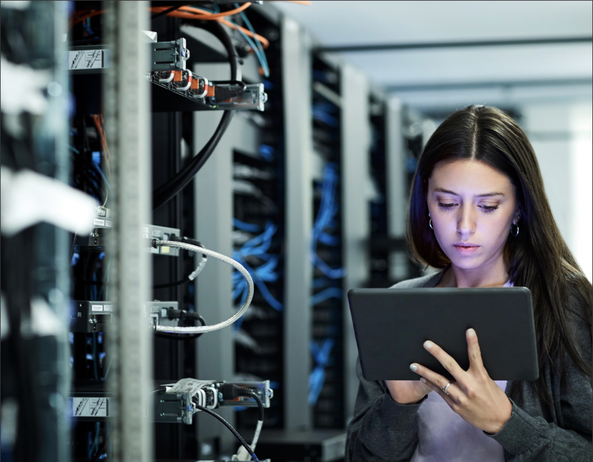 Female technician using digital tablet examining in server room